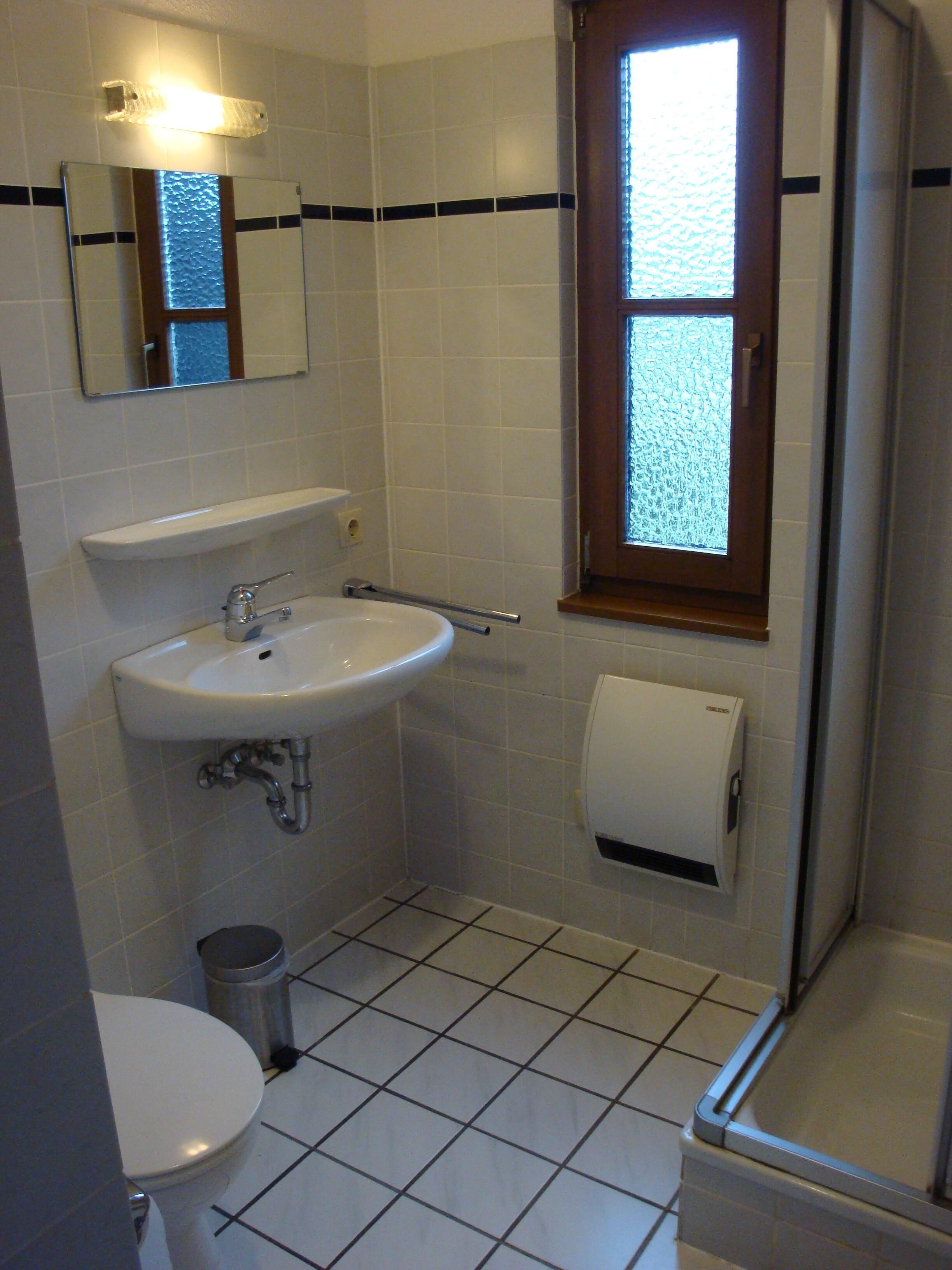 Een badkamer met een wit wastafel, spiegel, toilet en een raam met uitzicht op het water.