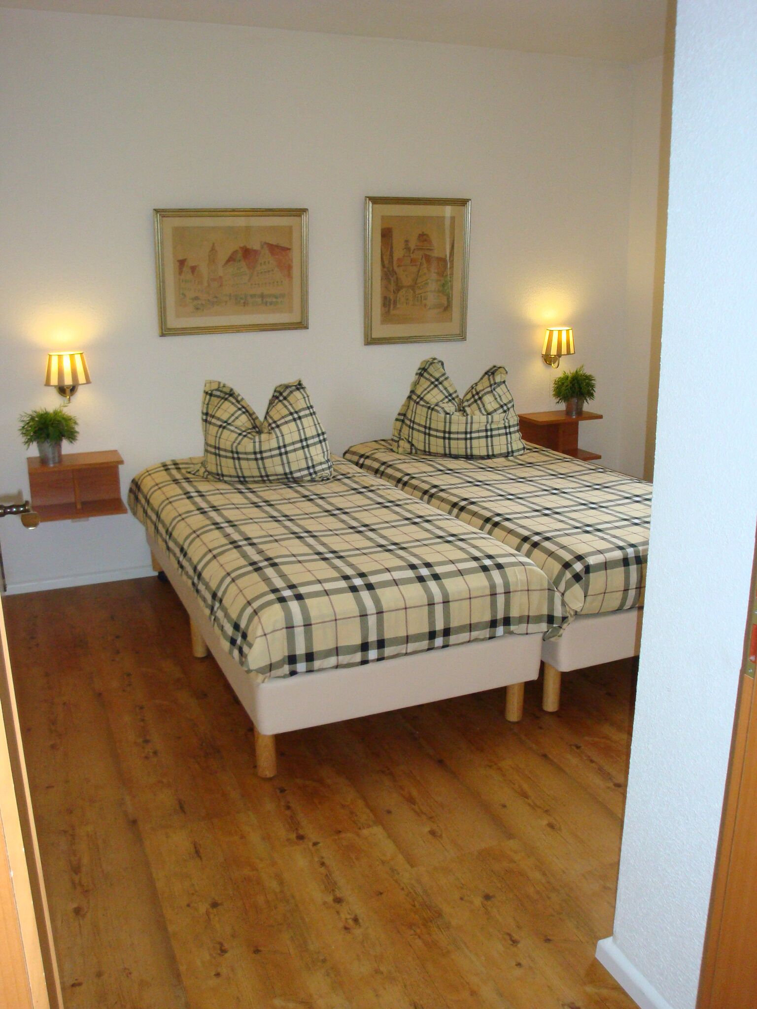 Ein Schlafzimmer mit zwei Betten, Holzboden und zwei Wandlampen.