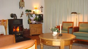 A cozy living room with a fireplace, a television, and comfortable seating. - Luxury holiday home, 100 meters from forest, swimming pool nearby, 4 km from Edersee (Frankenau)
