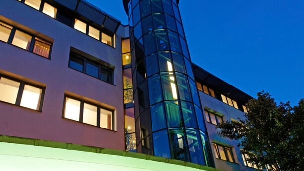 Ein Hotel mit moderner Gestaltung, erkennbar an der Glasfassade und dem roten Schild.