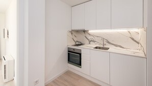 Et moderne køkken med hvide skabe, en marmorbordplade og indbyggede apparater.
