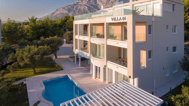 En moderne bygning med flere etager, der hedder "Villa 01", med en pool og udendørs siddepladser.