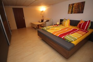 A bedroom with a bed, a nightstand, a chair, a desk, and a door. - Arrive and feel good, dogs are welcome! (Daxweiler)