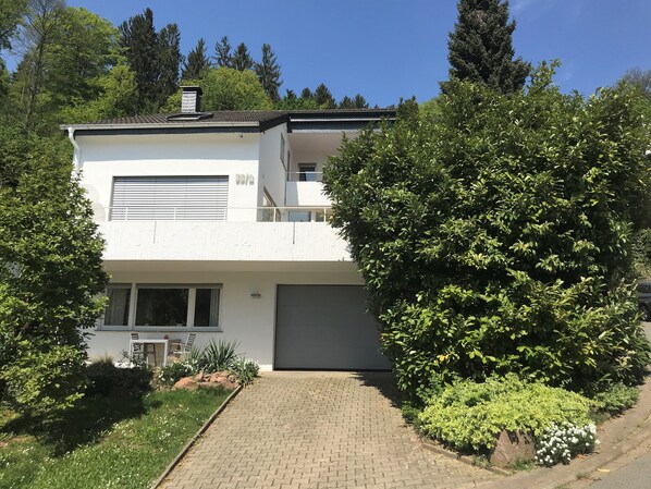 A modern two-story house with a paved driveway, surrounded by lush greenery and trees. - Close to the city live in the countryside with good access (Heidelberg)