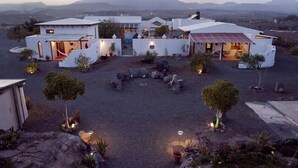 Una vila moderna amb diverses habitacions, un pati amb seients i vista a muntanyes llunyanes.