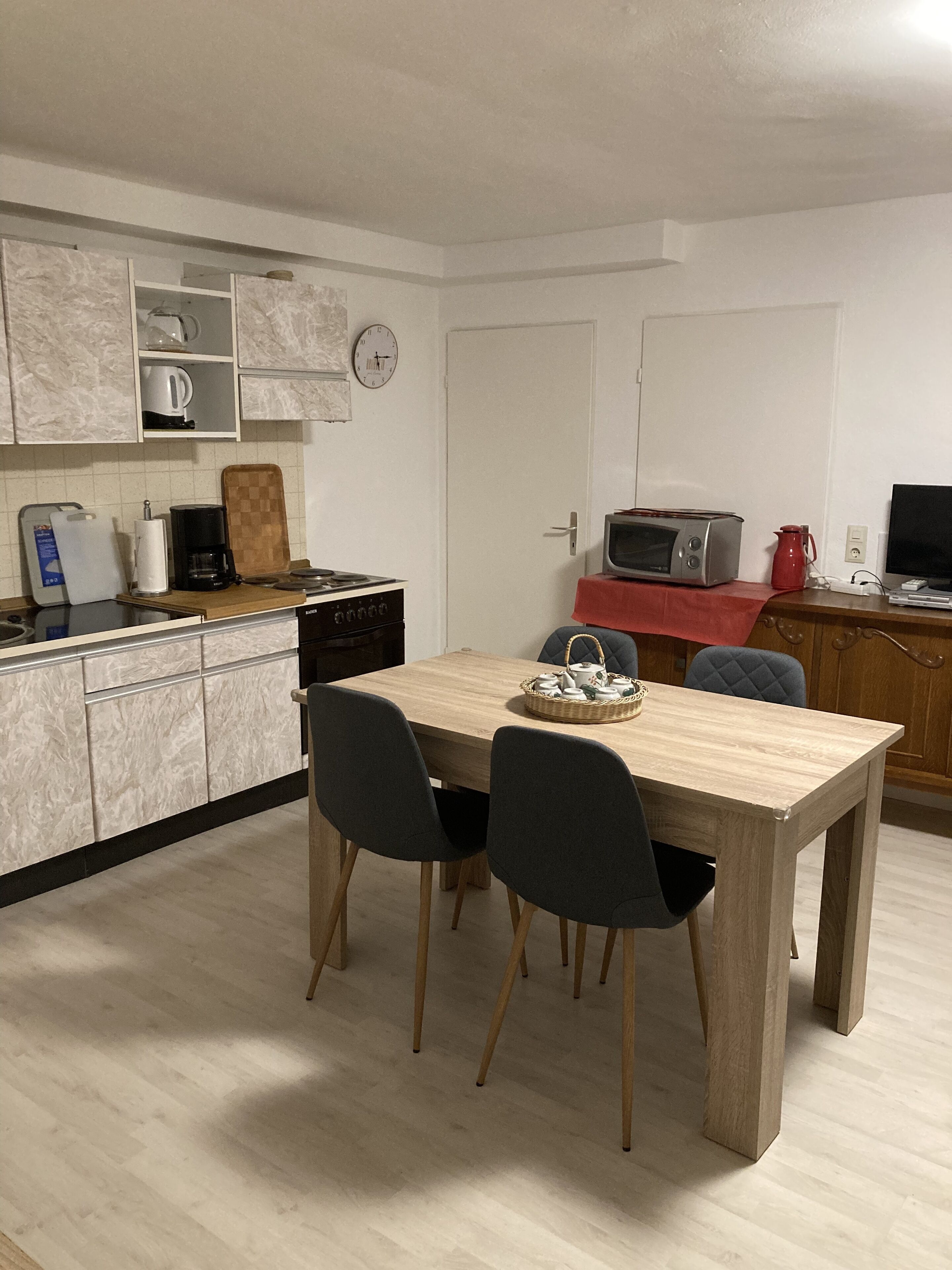 A compact kitchen with a dining table, chairs, and basic appliances.