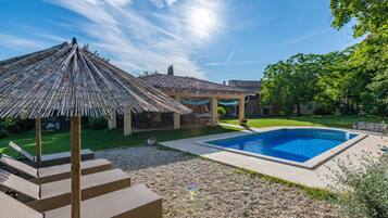 Una piscina al aire libre, sillones reclinables de piscina