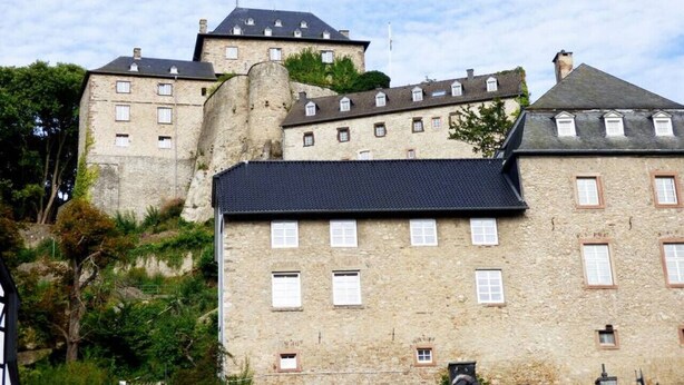 Un bâtiment en pierre doté de nombreuses fenêtres et d’une tour imposante.