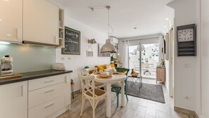 A modern kitchen with white cabinets, a dining table with chairs, and a chalkboard sign. - Sea View Apartment Windsor Park (Adeje)