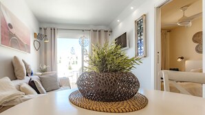 A modern living room with a white table, a decorative plant, and a view of the outside. - Sea View Apartment Windsor Park (Adeje)