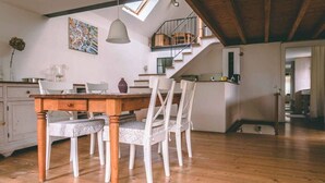 A dining area with a wooden table and white chairs, a staircase leading to an upper level, and a painting on the wall. - Old house to feel good (Usingen)