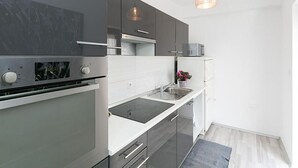 Moderni keittiö, jossa on sisäänrakennettu uuni, pesuallas ja työtaso.
