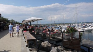 A marina with boats docked, a wooden pier with seating, and a clear sky.