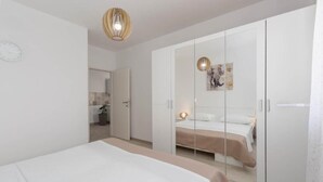 A bedroom with a bed, a wardrobe, and a mirror. - New charming and modern apartment Edi Premium White in Funtana (Funtana)