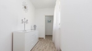 A narrow hallway with a white dresser, a wall clock, and a lamp. - New charming and modern apartment Edi Premium White in Funtana (Funtana)