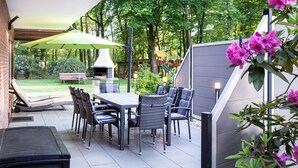 An outdoor patio with a dining table, chairs, and a grill. - Vacation apartment at Höpen - Lüneburg Heath (Schneverdingen)