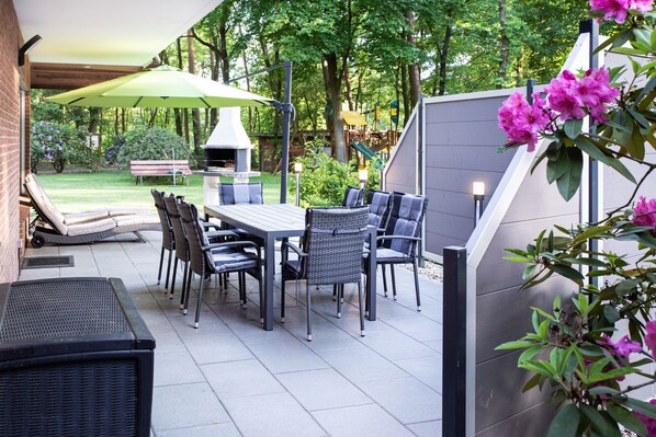An outdoor patio with a dining table, chairs, and a grill.