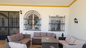 A cozy outdoor seating area with wicker furniture and metal gates. - Exclusive CHALET near SEVILLA Andalusia with pool for 14 people  (Lora del Río)