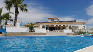 Una piscina al aire libre, sillones reclinables de piscina