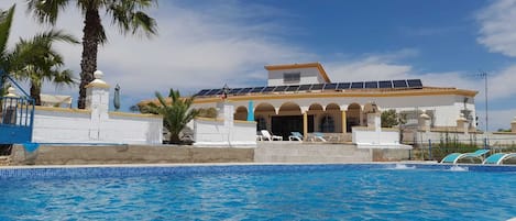 Una piscina al aire libre, sillones reclinables de piscina