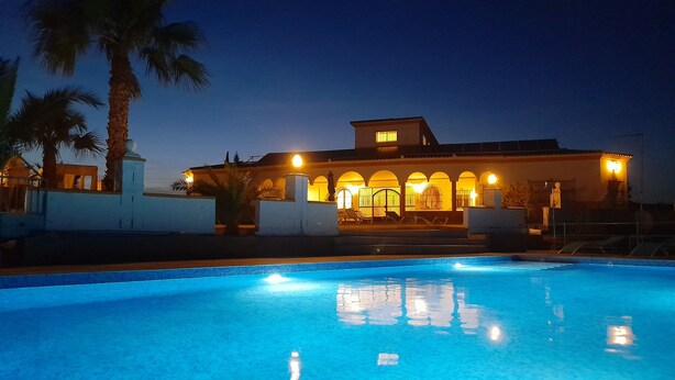 A swimming pool with a clear blue water surface, surrounded by a white wall and palm trees. - Exclusive CHALET near SEVILLA Andalusia with pool for 14 people  (Lora del Río)