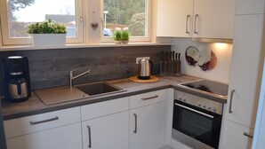 Una cocina moderna con armarios blancos, un lavamanos de acero inoxidable y un horno empotrado.