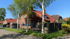 Un quartier résidentiel avec des maisons, une allée et une rue bordée d’arbres.