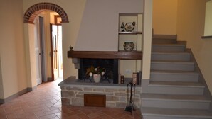 A staircase leading to a landing with a fireplace, a stone wall, and a tiled floor. - LA CASINA DEL BIONDO - LA CASINA DEL BIONDO (Monte San Savino)