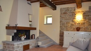 A cozy living room with a stone fireplace, a staircase, and a white sofa. - LA CASINA DEL BIONDO - LA CASINA DEL BIONDO (Monte San Savino)