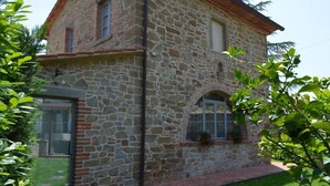 A stone building with a brick base, large windows, and a small garden area. - LA CASINA DEL BIONDO - LA CASINA DEL BIONDO (Monte San Savino)