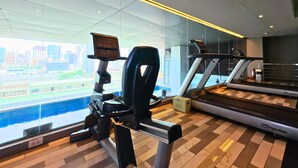Une salle de sport équipée d’un tapis de course, d’un vélo d’appartement et d’autres appareils d’exercice.