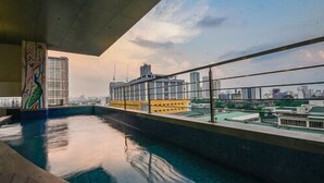 Une piscine intérieure avec vue sur la ville, un mur en verre et une fresque murale aux couleurs vives.