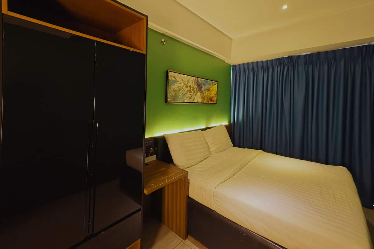Habitación de hotel con cama, armario de madera, mesita de noche, un cuadro en la pared y una cortina azul.