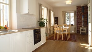 Eine Küche mit weißen Schränken, einer Holz Arbeitsplatte und einem Essbereich mit Tisch und Stühlen.