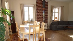 Ein Wohnzimmer mit einem Holzesstisch, Stühlen, einer Couch und einem gemusterten Teppich.