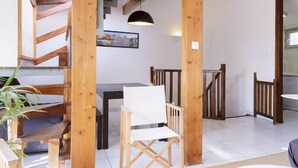 A spacious living area with a wooden staircase, a dining table, and a white armchair. - Vieux Port to Notre Dame de la Garde Triplex 70 m2 terrace (Marseille)