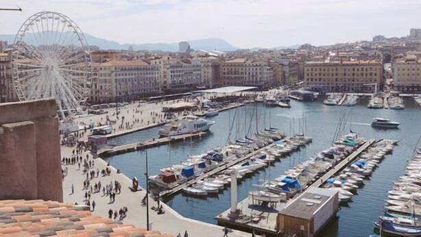 A marina with boats docked, a Ferris wheel, and buildings in the background. - Vieux Port to Notre Dame de la Garde Triplex 70 m2 terrace (Marseille)