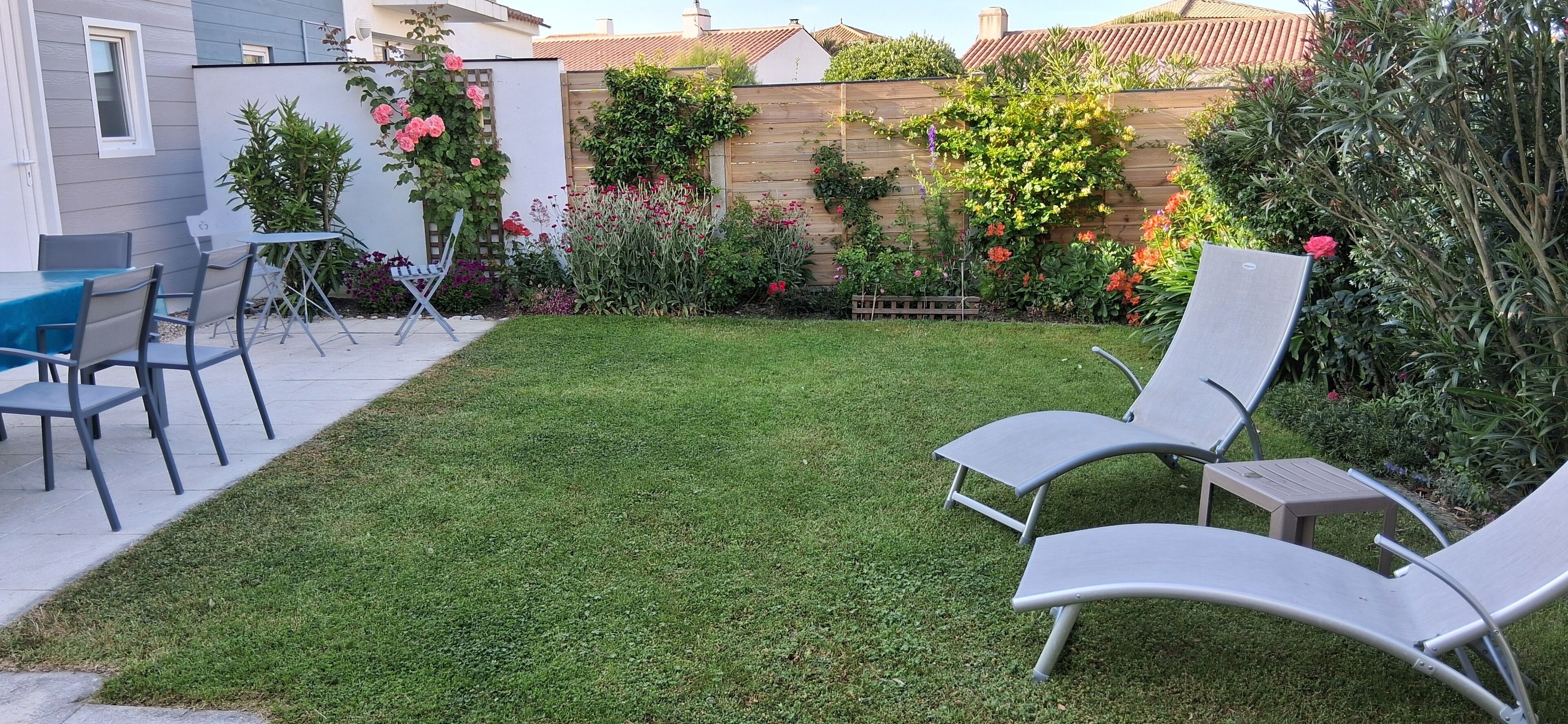 A backyard with a well-maintained lawn, two lounge chairs, and a small table.