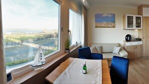 A modern room with a large window, a sailboat model, a bottle, a sofa, and a cabinet.