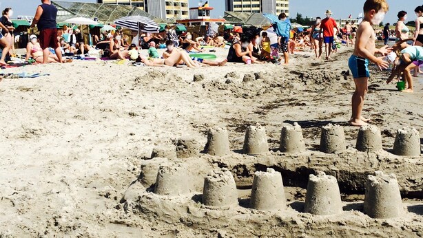 A sandy beach with people and beach umbrellas.