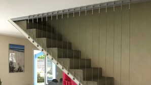 A staircase with a modern design, a red accent wall, and a vintage trunk in the foreground.