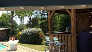 A wooden deck with a pool, outdoor bar, and seating area.