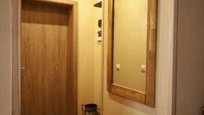 A narrow hallway with a wooden door, a mirror on the wall, and a patterned rug on the floor. - Vacation apartment for 4 max. 5 persons in Arnstadt. Wallbox 0.59 KW (Arnstadt)