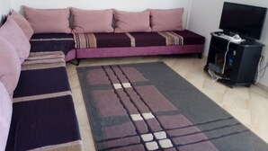 Un salon comprenant un canapé, un téléviseur et un tapis.