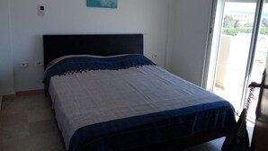 Une chambre avec un lit, un tableau au mur et une porte coulissante donnant sur l’extérieur.