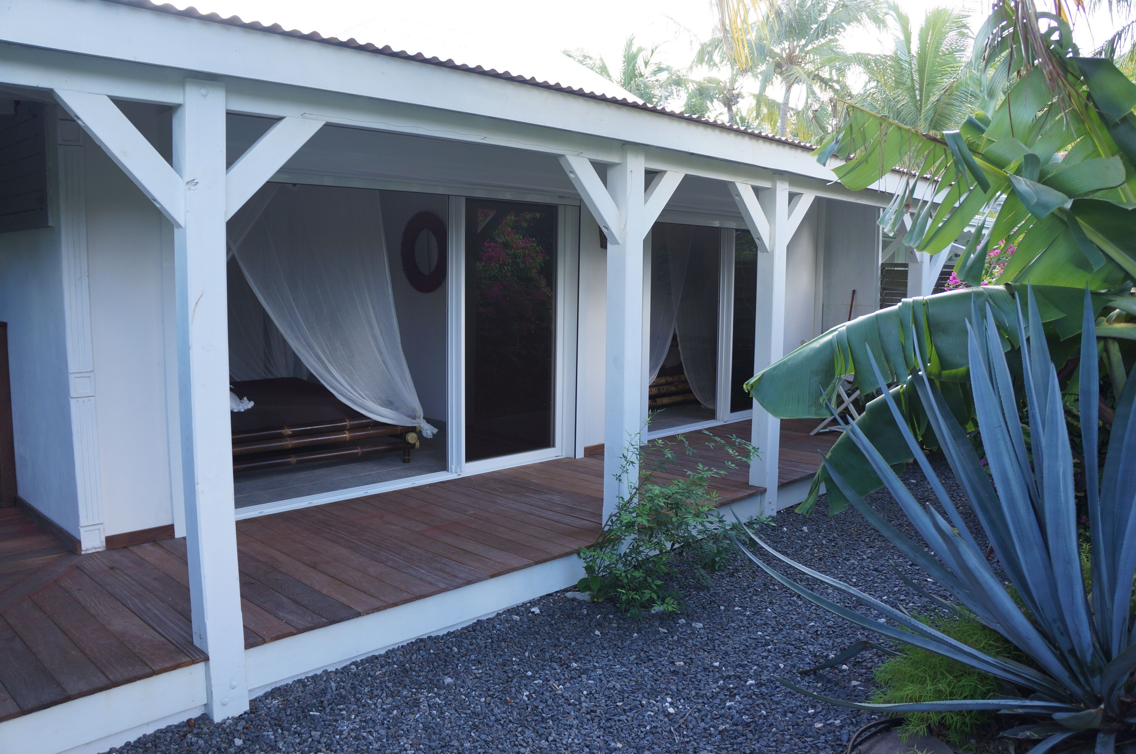 A white building with a wooden deck and covered outdoor seating area.