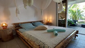 Ein Schlafzimmer mit Bett, Nachttischen, einer Nachttischlampe und Blick ins Freie.