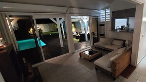 Ein geräumiger Wohnbereich mit einer Couch, einem Couchtisch und einer Schiebetür zu einem Pool.