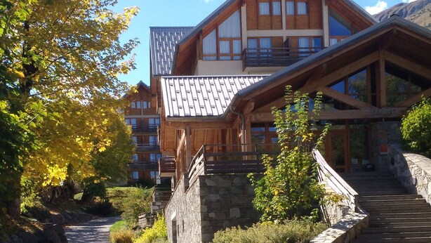 Una cabaña de madera con una escalera de piedra que conduce a una terraza de madera.