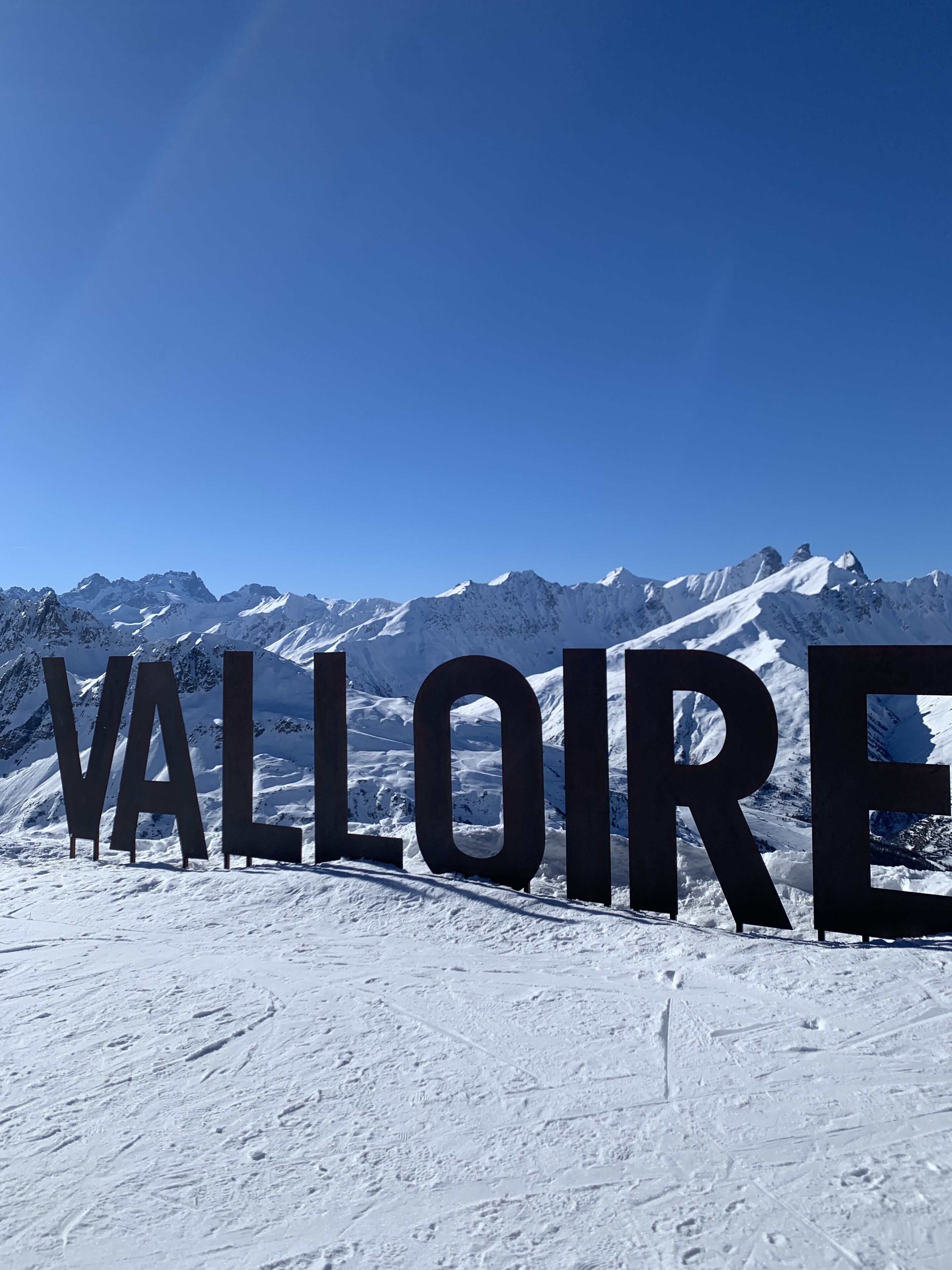 A snowy landscape with large letters spelling "VALLOIRE" in the foreground.